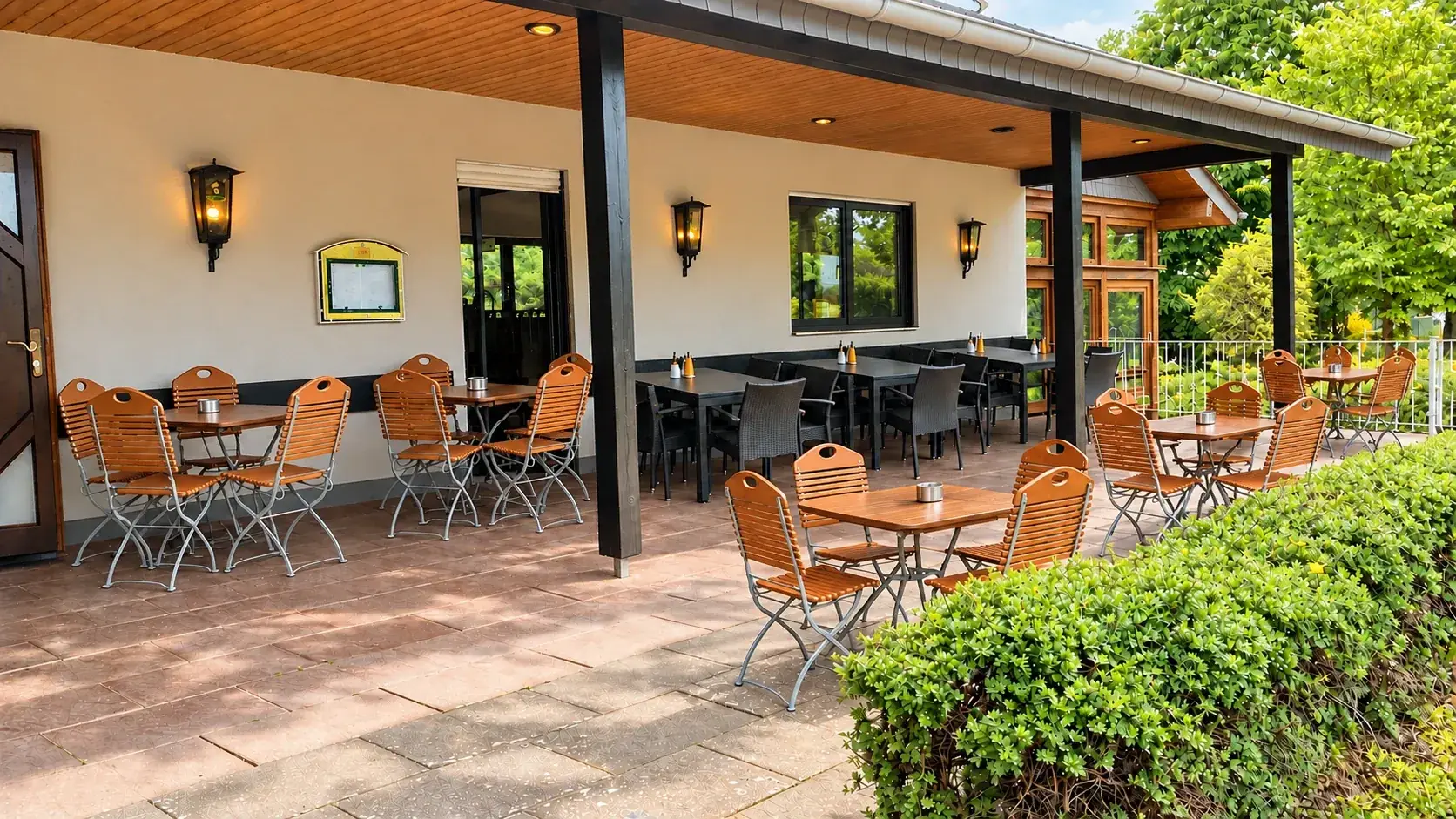 Überdachte Terrasse am Clubhaus mit Holzstühlen und Blick ins Grüne